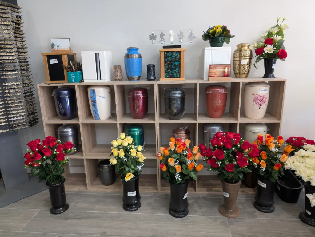 Urnes funéraires et bouquets de fleurs sur étagères en bois.
